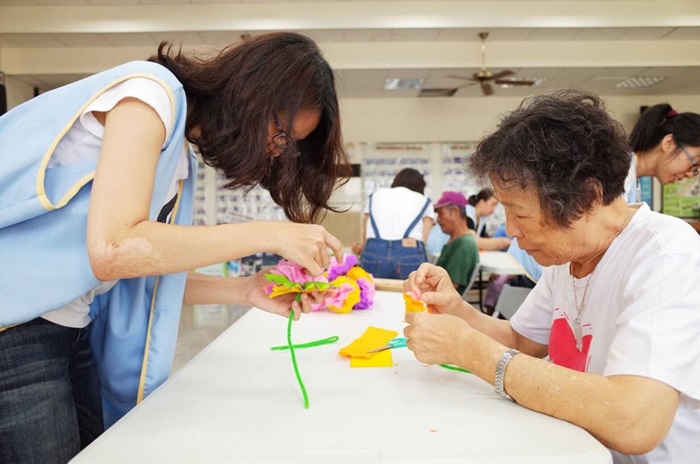 服務隊成員與居民奶奶一同摺康乃馨